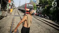 Seorang pria berjemur di bantaran rel di kawasan pemukiman padat Pejompongan, Jakarta, Selasa (6/7/2021). Berjemur diri di bawah matahari di antara pukul 08.00-11.00 WIB merupakan salah satu upaya yang paling sederhana untuk menjaga kesehatan selama wabah virus COVID-19. (Liputan6.com/Faizal Fanani