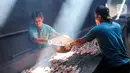 Pekerja membawa ikan lele yang akan diasapkan menggunakan kayu bakar di Desa Pengasinan, Gunung Sindur, Bogor, Rabu (30/9/2020). Pengasapan lele satu-satunya di wilayah Bogor dijual Rp 100.000 per kg yang berisi sekitar 25 ekor. (Liputan6.com/Fery Pradolo)