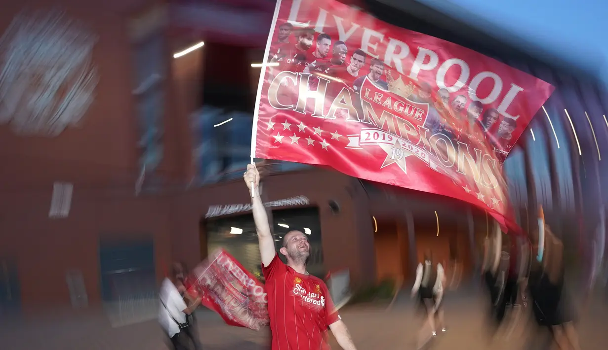 Seorang pendukung Liverpool merayakan gelar juara Liga Premier di luar Stadion Anfield, Kamis (25/6/2020). Trofi juara Liga Primer musim 2019-2020 Trofi juara Liga Primer musim 2019-2020 tersebut dimenangkan Liverpool setelah Manchester City takluk 1-2 dari Chelsea. (AP/Jon Super)