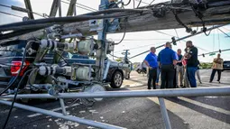Sejumlah tiang listrik tampak bertumbangan akibat hantaman badai tersebut. Beberapa kendaraan rusak akibat tertimpa tiang listrik yang tumbang. (Jerry Jackson/The Baltimore Sun via AP)