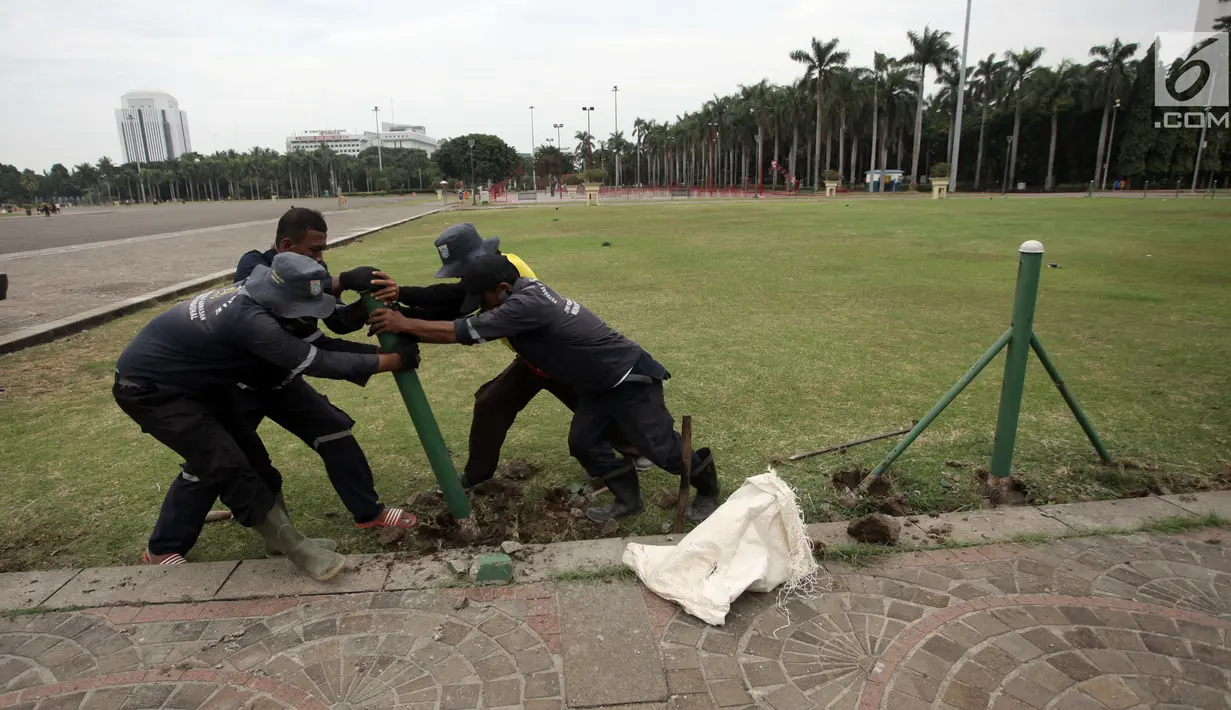 Petugas Unit Pengelola Kawasan (UPK) Monas mencabut pagar pembatas rumput di dalam kawasan Monas, Jakarta, Jumat (11/1). Langkah ini dilakukan Pemprov DKI untuk memberi akses kepada warga agar bisa memanfaatkan taman di sana. (Liputan6.com/Arya Manggala)