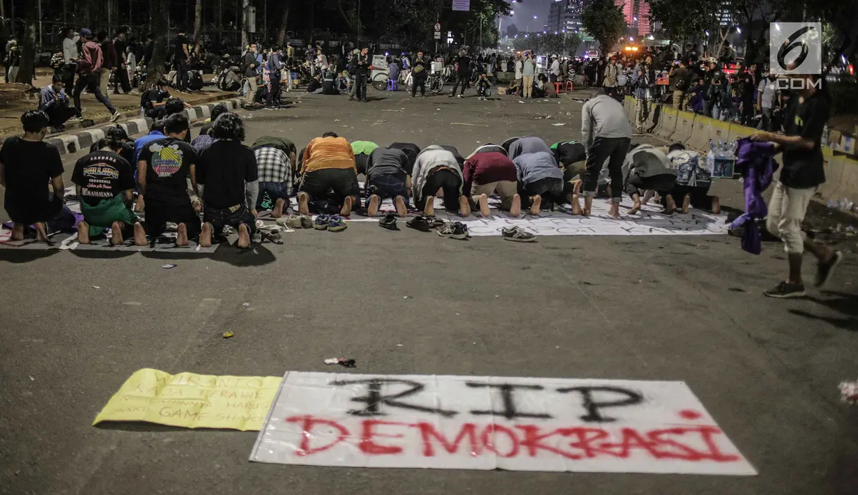 Massa dari Badan Eksekutif Mahasiswa Seluruh Indonesia (BEM SI) melakukan salat magrib disela unjuk rasa di depan gedung DPR/MPR RI, Jakarta, Selasa (1/10/2019). Di sela-sela agenda pelantikan anggota baru DPR RI 2019-2024, gelombang mahasiswa kembali menggelar demo. (Liputan6.com/Faizal Fanani)