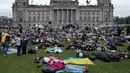 Orang-orang berbaring di tanah melambangkan mereka yang tewas dalam perang di Ukraina selama demonstrasi menentang invasi Rusia, di depan gedung Reichstag di Berlin, Jerman, 6 April 2022. Pengunjuk rasa menuntut Berlin berhenti membeli minyak dan gas Rusia. (AP Photo/Markus Schreiber)