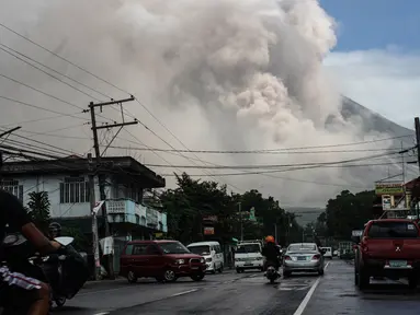 Pengendara melintasi jalanan ketika gunung Mayon mengeluarkan gumpalan asap raksasa di Camalig, selatan Manila, Senin (22/1). Filipina menaikkan Status Gunung Mayon menjadi level 4 setelah memuntahkan abu vulkanis setinggi 10 kilometer. (AFP PHOTO/STR)