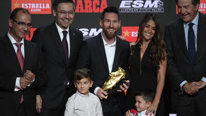 Pemain Barcelona, Lionel Messi (tengah) berpose bersama istrinya Antonella Roccuzzo dan putra-putranya Thiago dan Mateo setelah menerima trofi Sepatu Emas keenamnya selama acara penyerahan di Antiga Fabrica Estrella Damm, Barcelona, Spanyol (16/10/2019). (AFP Photo/Josep Lago)