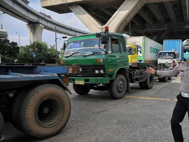 Polisi Lalu Lintas dan Dinas Perhubungan Daerah Khusus Jakarta melakukan pengaturan keluar masuk kendaraan truk kontainer di area Perempatan Pos IX Pelabuhan Tanjung Priok, Jakarta Utara, Jumat (18/4/2025). (Liputan6.com/Angga Yuniar)