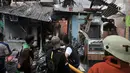 Warga menjinakkan kobaran api yang membakar permukiman di kawasan Tanah Tinggi, Johar Baru, Jakarta, Selasa (26/6). Sejumlah warga memilih mengungsi ke pinggir rel yang berada tidak jauh dari lokasi kebakaran. (Merdeka.com/Iqbal Nugroho)
