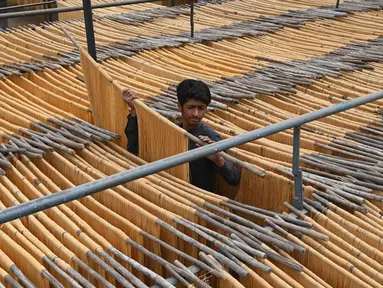 Seorang pekerja mengeringkan bihun yang digunakan untuk membuat hidangan manis tradisional yang populer selama bulan puasa Ramadhan di Lahore, Pakistan, 12 April 2022. (Arif ALI/AFP)