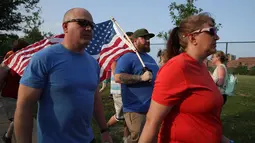 Sejumlah warga berjalan membawa bendera AS saat menggelar aksi solidaritas terkait penembakan di Virginia, AS (14/6). Sebelumnya telah terjadi penembakan terhadap politisi Partai Republik, Steve Scalise saat berlatih bisbol. (Alex Wong/Getty Images/AFP)