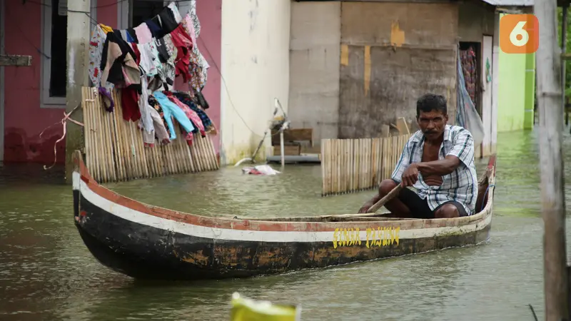 Deri Mustapa, warga Desa Buhu, Kecamatan Telaga Jaya, Kabupaten Gorontalo saat mengayuh perahu menuju rumahnya (Arfandi/Liputan6.com)