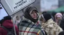 Seorang wanita membungkus dirinya dengan selimut agar tetap hangat saat menunggu di kerumunan pengungsi setelah melarikan diri dari Ukraina dan tiba di perbatasan di Medyka, Polandia, Senin (7/3/2022). Hampir 2 juta orang melarikan diri dari Ukraina sejak invasi Rusia. (AP Photo/Markus Schreiber)