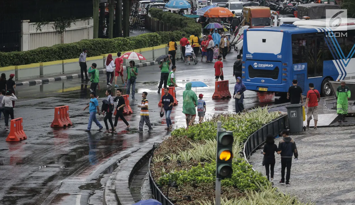 Sejumlah warga melakukan aktivitas saat kegiatan rutin hari bebas kendaraan bermotor atau car free day (CFD) dikawasan Bunderan HI, Jakarta, Minggu (4/2). Warga tetap melanjutkan aktivitasnya walaupun gerimis mengguyur. (Liputan6.com/Faizal Fanani)