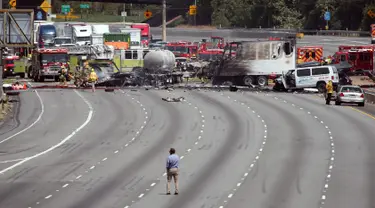 Penyidik memeriksa bangkai truk yang telah hangus usai terjadi tabrakan antara dua truk besar di utara pusat kota Los Angeles (25/4). Kecelakaan ini menewaskan satu orang dan melukai sejumlah orang lainnya. (AP Photo/Reed Saxon)