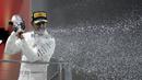 Pebalap Mercedes, Lewis Hamilton  menyemprotkan champagne saat menerima penghargaan di podium pada balapan F1 Singapura di Marina Bay City Circuit Singapore, (17/9/2017).  (AP/Wong Maye-E)