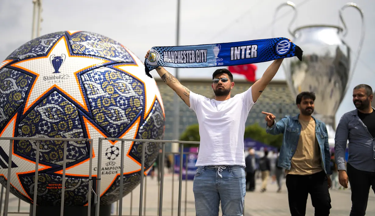 Seorang pengunjung berpose dengan membentangkan syal yang bergambar Inter Milan dan Manchester City di Istanbul, Turki, Kamis (8/6/2023). Laga final yang mempertemukan Inter Milan melawan Manchester City akan berlangsung di Atatürk Olympic Stadium, Istanbul, Turki, Minggu (9/6/2023) dini hari WIB. (AP Photo/Francisco Seco)