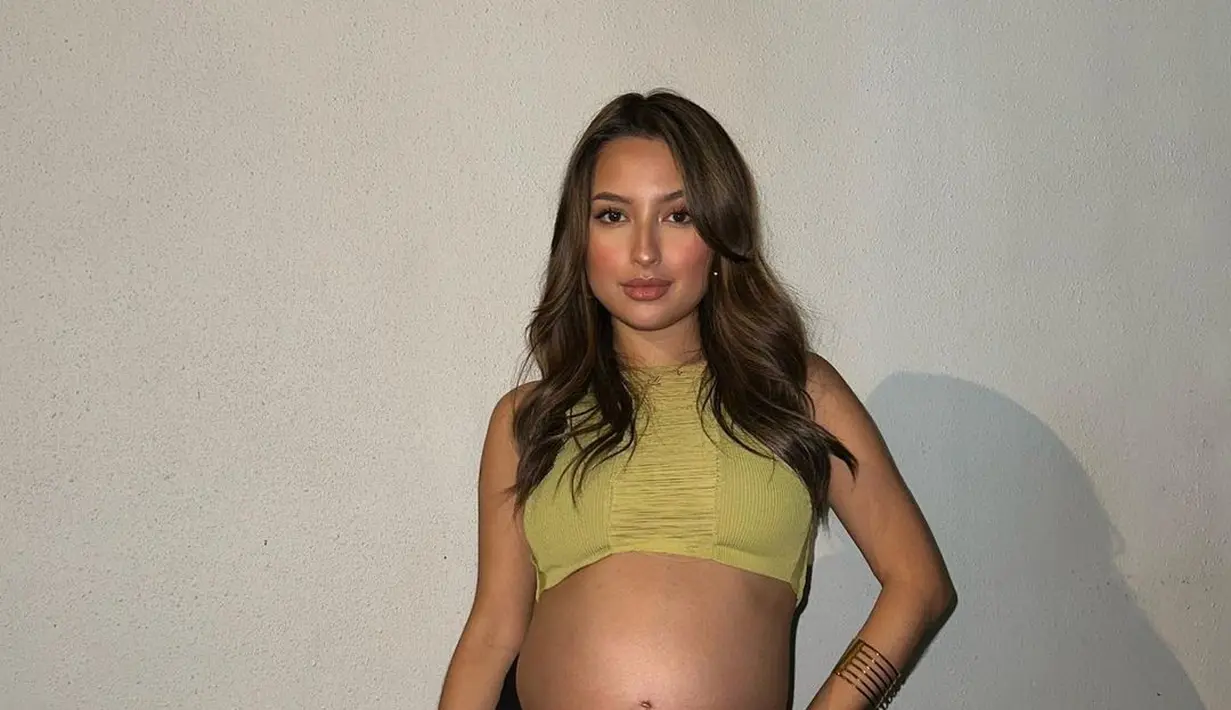 Jennifer Coppen tampil dengan sleeveless cropped top berwarna kekuningan. Pamer baby bumps dengan kulit eksotis dipadu dengan long skirt hitam yang memiliki high-slit. Foto: Instagram.