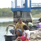 Sembari mengasuh anak, ibu-ibu nekat mencuci di bibir Waduk Sangge. Foto: (Felek/Liputan6.com)