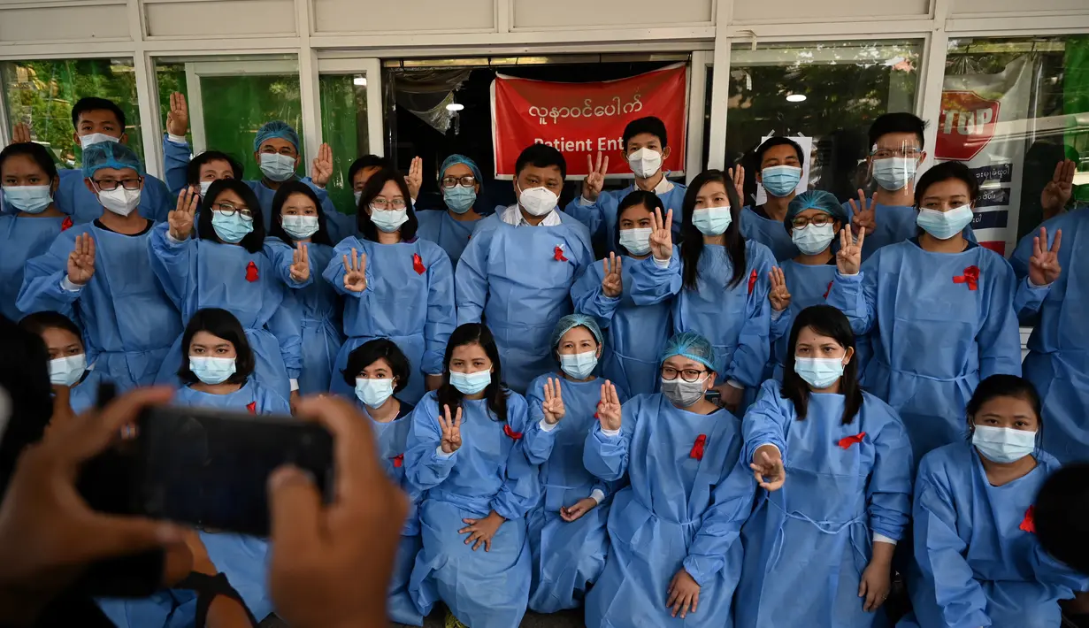 Tenaga medis mengenakan pita merah di seragamnya memberi hormat tiga jari di Rumah Sakit Umum Yangon di Yangon (3/2/2021). Petugas kesehatan di 70 rumah sakit dan departemen medis di Naypyidaw, Yangon dan kota-kota lain mengatakan, mereka tidak akan bekerja di bawah rezim militer. (STR / AFP)
