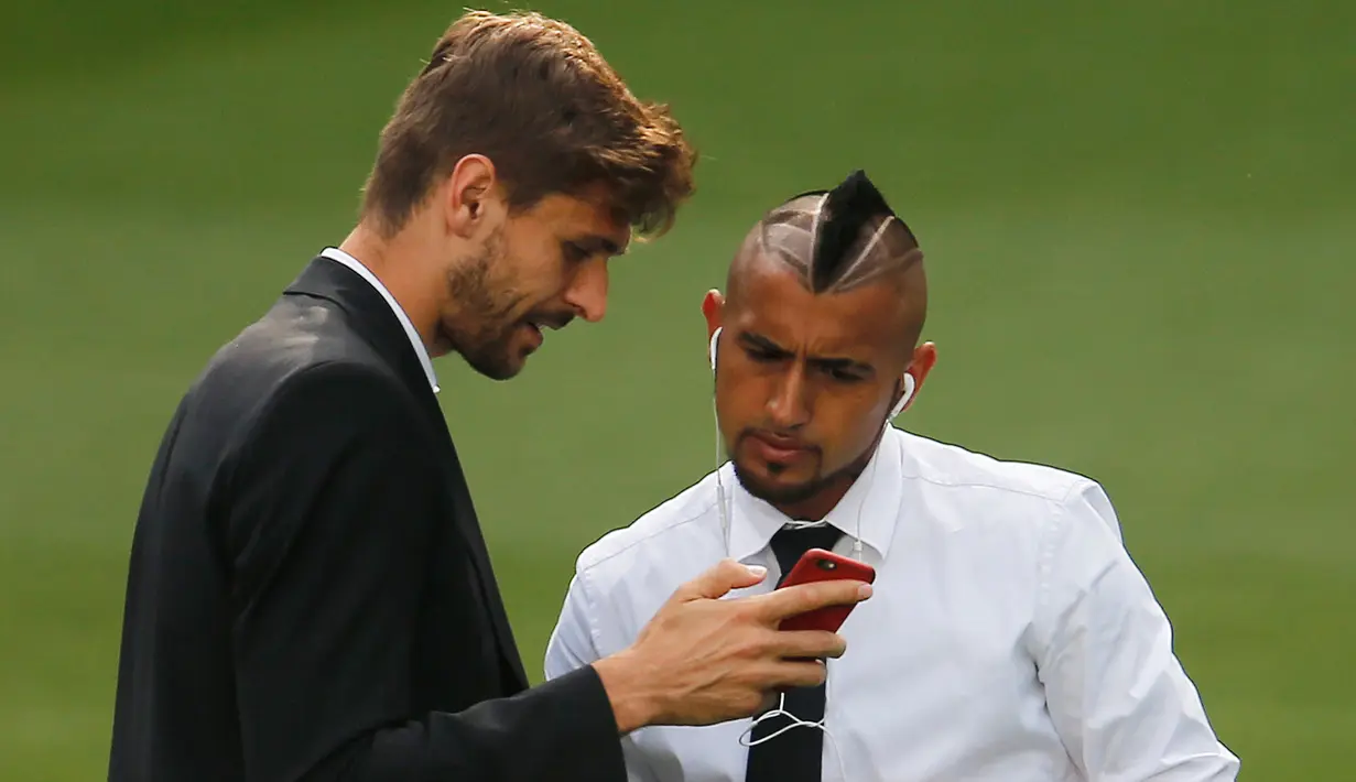 Penyerang Juventus, Fernando Llorente menunjukkan handphone ke Arturo Vidal jelang konferensi pers di Stadion Santiago Bernabeu, Spanyol (12/5/2015). Juventus akan menantang Real Madrid di leg kedua semifinal Liga Champions.  (Reuters/Sergio Perez)