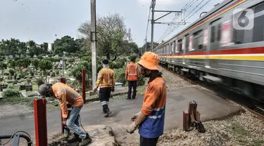 Pekerja PT KAI menyelesaikan pemasangan pembatas jalan di perlintasan kereta tanpa palang pintu di kawasan TPU Tanah Kusir, Jakarta, Kamis (17/9/2020). Pemasangan pembatas jalan dilakukan untuk mencegah kecelakaan kendaraan yang sering terjadi di kawasan tersebut. (merdeka.com/Iqbal S. Nugroho)