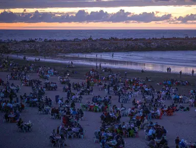 Warga buka puasa bersama keluarga dan kerabat sambil menikmati matahari terbenam di pantai Rabat, Maroko (9/6). Selama Ramadan, banyak warga Maroko berkunjung ke pantai menikmati angin Atlantik dan menikmati pemandangan laut. (AP Photo/Mosa'ab Elshamy)