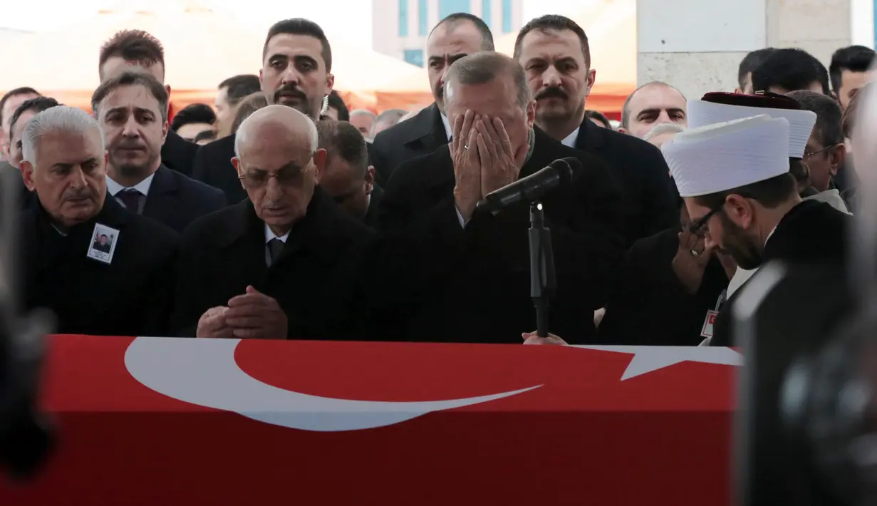 Presiden Turki Recep Tayyip Erdogan menutupi wajah sambil berdoa saat menyalati tentara Turki pertama yang tewas dalam operasi 'Ranting Zaitun' di Suriah, Ankara, Turki, Selasa (23/1). Tentara tewas bernama Sersan Musa Ozalkan. (Foto AP/Burhan Ozbilici)