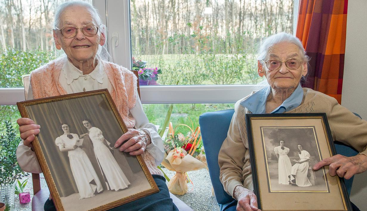 Paulette Olivier (kiri) dan Simone Thiot memperlihatkan foto semasa muda di Ephad "Les Bois Blancs", Prancis (13/2). Paulette dan Simone lahir pada 30 Januari 1912 di Limeray, beberapa kilometer dari Amboise. (AFP PHOTO/GUILLAUME souvent)
