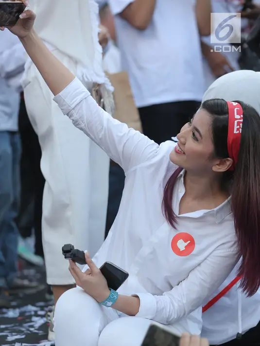 Artis Asty Ananta berselfie saat menghadiri kampanye akbar pasangan Capres dan Cawapres nomor urut 01, Jokowi - Ma'ruf Amin bertajuk 'Konser Putih Bersatu di Stadion Gelora Bung Karno (SGBK), Jakarta, Sabtu (13/4). (Kapanlagi.com/Budi Santoso)