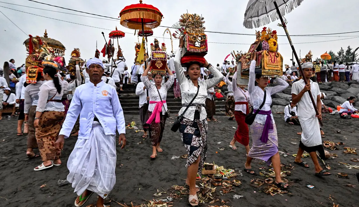 Umat Hindu berjalan untuk berdoa sambil membawa persembahan saat upacara Melasti di sebuah pantai di Denpasar, Bali, pada Rabu 26 Maret 2025. (Sonny TUMBELAKA/AFP)