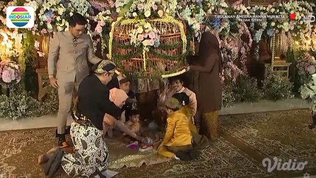Atta Halilintar dan Aurel Hermansyah mendampingi putri mereka Ameena Hanna Nur Atta menjalani upacara Tedak Siten di acara 7 bulanan. (Foto: Indosiar/Vidio)