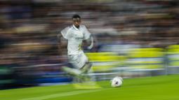 Penyerang Real Madrid, Vinicius Junior berlari membawa bola saat bertanding melawan Cadiz selama pertandingan lanjutan La Liga Spanyol di stadion Santiago Bernabeu di Madrid, Jumat (11/11/2022). Tambahan tiga poin ini membuat Madrid terus menempel Barcelona di puncak klasemen La Liga. (AP Photo/Manu Fernandez)