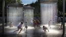 Anak-anak mendinginkan diri di air mancur umum di Vilnius, Lithuania, 26 Juni 2022. Gelombang panas berlanjut di Lithuania saat suhu naik hingga 32 derajat Celcius (89,6 derajat Fahrenheit). (AP Photo/Mindaugas Kulbis)