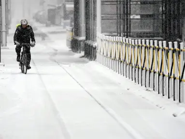 Seorang pria mengendarai sepeda melalui jalan yang tertutup salju di Beograd, Serbia, Minggu (12/12/2021).  Ahli meteorologi memperkirakan hujan salju lebat dan suhu di bawah nol di Balkan Barat sepanjang minggu. (AP Photo/Darko Vojinovic)