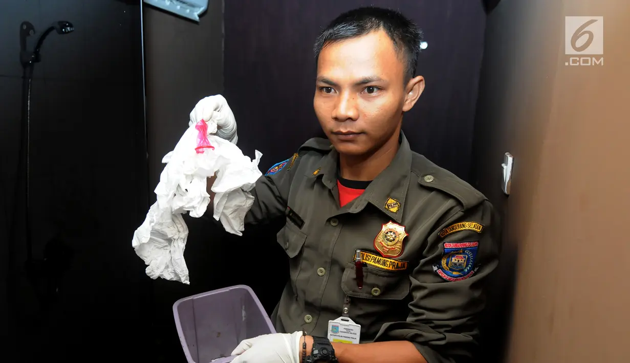 Petugas Satpol PP membawa alat kontrasepsi saat razia panti pijat di BSD, Tangerang Selatan, Selasa (25/6/2019). Dalam razia tersebut ditemukan sepasang pria dan wanita tanpa busana dalam kamar. (merdeka.com/Arie Basuki)