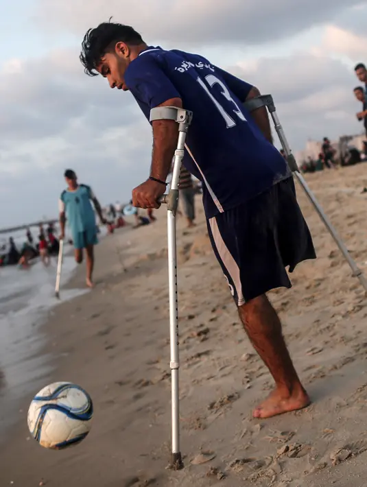 Pemuda Palestina Ahmed al-Khoudari berusaha mengontrol bola saat bermain dengan kawannya Mohammed Eliwa  di pantai di Kota Gaza (20/9/2019). Eliwa 17 tahun dan Ahmed al-Khoudari 20 tahun kehilangan satu kakinya saat bentrok di perbatasan Israel. (AFP Photo/Mahmud Hams)