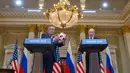 Presiden AS Donald Trump menerima bola dari Presiden Rusia Vladimir Putin pada konferensi pers bersama di Helsinki, Finlandia, Senin (16/7). Bola itu sebagai penghormatan karena AS akan menjadi tuan rumah Piala Dunia 2026. (AP/Pablo Martinez Monsivais)