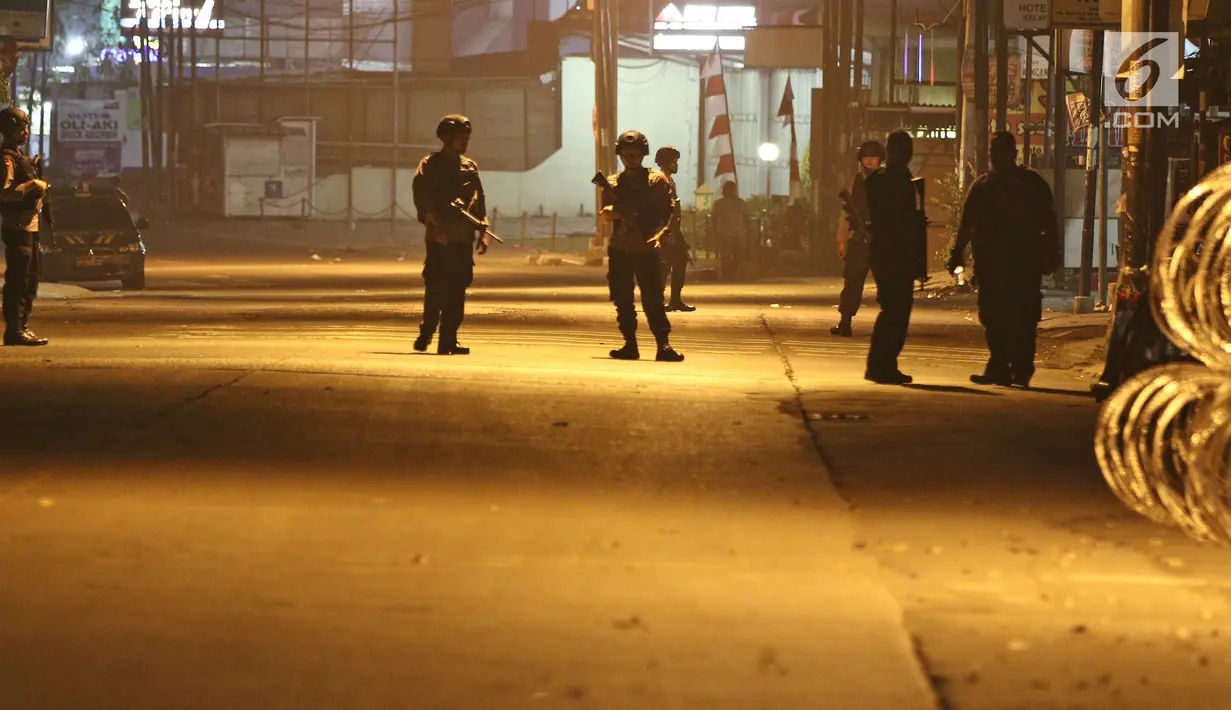 Anggota kepolisian berjaga di depan Mako Brimob Kelapa Dua pascabentrok antara petugas dengan tahanan di Depok, Kamis (10/5) dini hari. Menjelang subuh, iring-iringan kendaraan polisi masuk ke dalam area Mako Brimob. (Liputan6.com/Herman Zakharia)