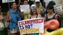 Sejumlah wanita mengenakan pakaian renang sambil memegang papan protes saat menggelar aksi di depan kedutaan Prancis di London, Inggris, Kamis (25/8). Mereka memprotes larangan burkini yang diberlakukan di kota-kota pesisir di Prancis. (REUTERS/Neil Hall)