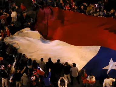 Sejumlah suporter Chili mengibarkan bendera nasional Chili merayakan kemenangan Chili atas Argentina di final Copa Amerika 2015 di Santiago, (4/7/2015). Chili menang lewat adu penalti atas Argentina dengan skor 4-1. (REUTERS/Carlos Garcia Rawlins)