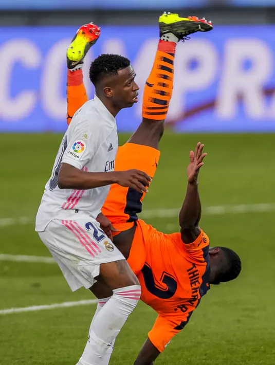 Pemain Valencia Thierry Correia jatuh di samping pemain Real Madrid Vinicius Junior pada pertandingan Liga Spanyol di Stadion Alfredo Di Stefano, Madrid, Spanyol, Minggu (14/2/2021). Real Madrid menggeser Barcelona di peringkat dua klasemen usai menaklukkan Valencia 2-0. (AP Photo/Manu Fernandez)