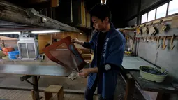 Seorang pengrajin bernama Yuichi Hirose menunjukkan cetakan stensil yang digunakan untuk mewarnai kain putih menjadi kimono di Tokyo, Jepang (1/3). Kimono adalah pakaian tradisional Jepang yang berasal dari era Muromachi (1392-1568). (AFP/Kazuhiro Nogi)