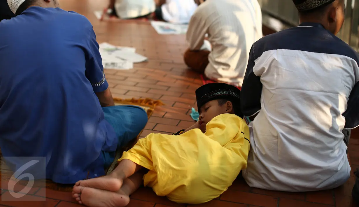 Seorang anak kecil tertidur ketika mendengarkan khutbah salat Idul Fitri di Masjid Istiqlal, Jakarta, Rabu (6/7). Wapres Jusuf Kalla serta sejumlah anggota kabinet juga melaksanakan salat Ied di masjid tersebut. (Liputan6.com/Faizal Fanani)