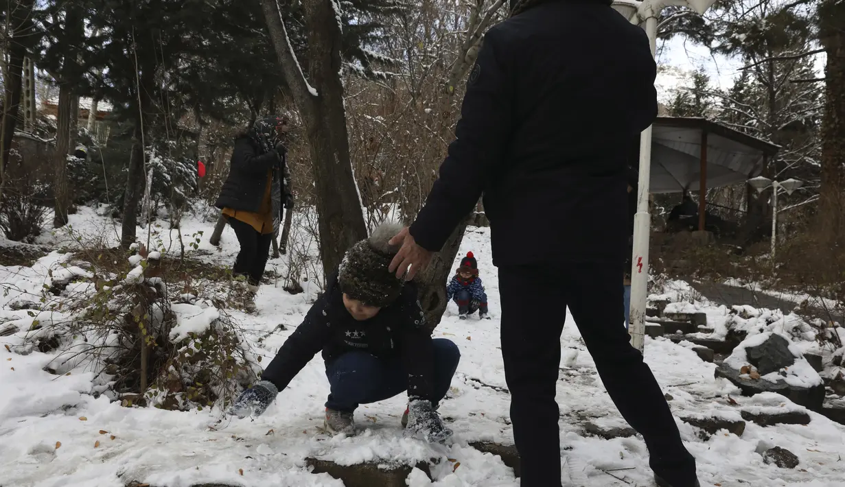 Seorang anak laki-laki bermain salju bersama keluarganya saat menghabiskan akhir pekan mereka di sebuah taman di Teheran utara, Iran, Jumat (25/12/2020). Musim dingin di Iran biasanya dimulai dari bulan Desember hingga Februari.  (AP Photo/Vahid Salemi)