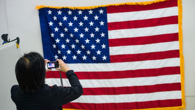 Pekerja memotret bendera Amerika Serikat di National Capital Flag Company, Alexandria Virginia, AS (10/1). Dalam acara tersebut Trump akan memberikan pidato resmi pertamanya sebagai presiden setelah membacakan sumpah. (AFP/Andrew Caballero Reynolds)