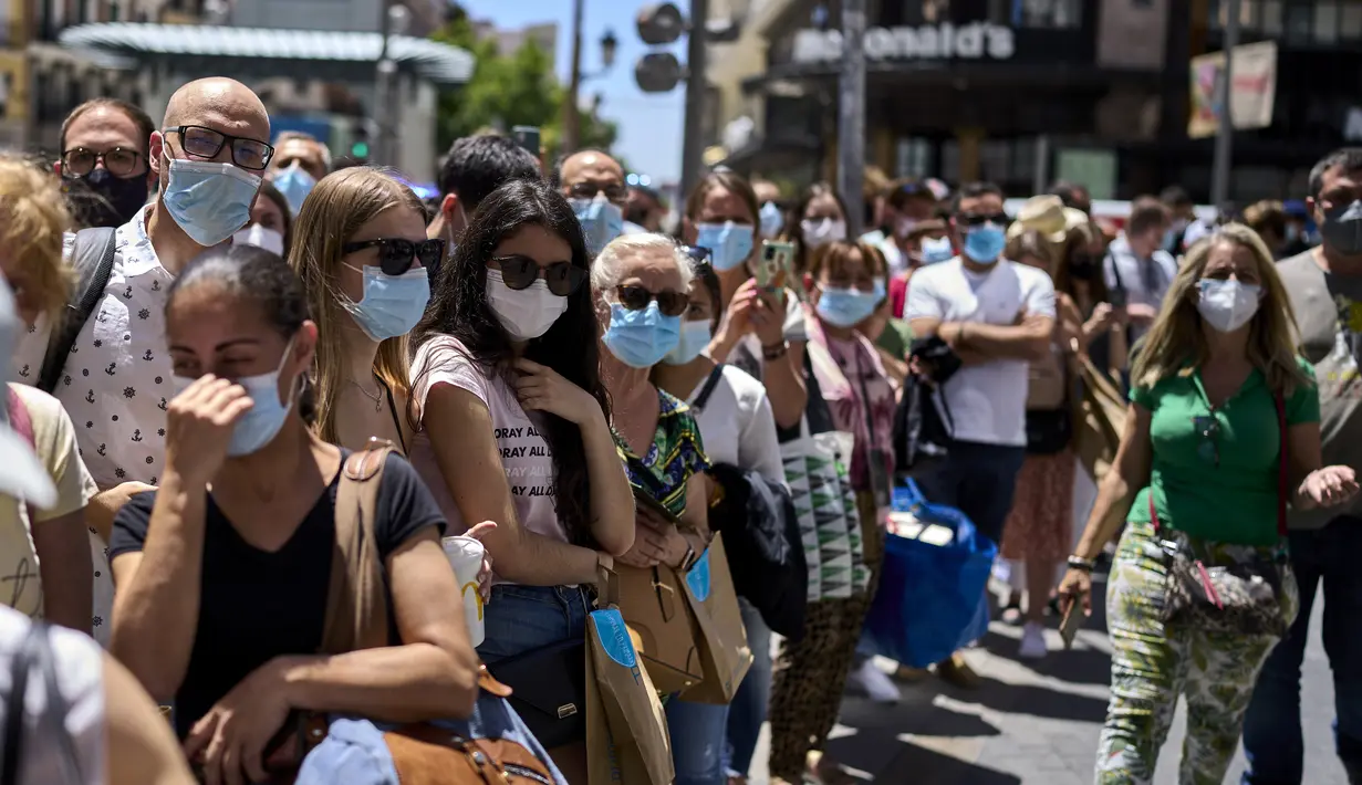Orang-orang yang memakai masker berdiri di sepanjang jalan di Madrid, Spanyol, Kamis (24/6/2021). Spanyol melonggarkan aturan pandemi COVID-19, mengizinkan orang berhenti mengenakan masker di luar ruangan dan mengizinkan penggemar olahraga kembali ke dalam stadion.  (AP Photo/Manu Fernandez)