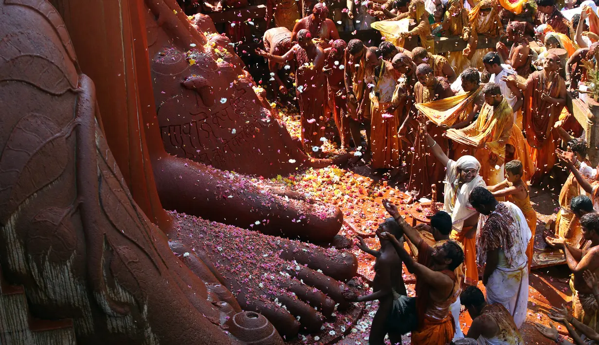 Para bhakta mengumpulkan kelopak bunga yang ditaburi dari patung Dewa Jain di Shravanabelagola, di barat Bangalore, India (18/2). Ratusan ribu pemuja Jain menghadiri Mahamastabhisheka ini. (AP Photo/Aijaz Rahi)