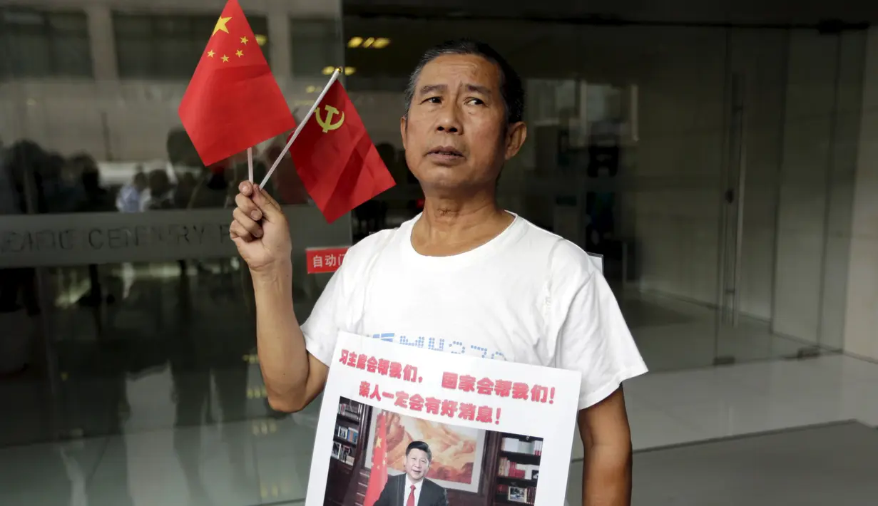 Keluarga penumpang MH370 membawa poster bergambar Presiden China di depan kantor Malaysia Airlines, Beijing, Kamis (6/8). Pemerintah Malaysia telah resmi menyatakan puing pesawat di Pulau Reunion adalah bagian dari MH370. (REUTERS/Jason Lee)
