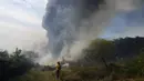 Seorang petugas pemadam kebakaran sukarela menggunakan tusukan dari selang untuk membasahi sisa-sisa gubuk yang terbakar selama kebakaran semak di lingkungan Banco San Miguel di Asuncion, Paraguay (18/1/2022). (AP Photo/Jorge Saenz)