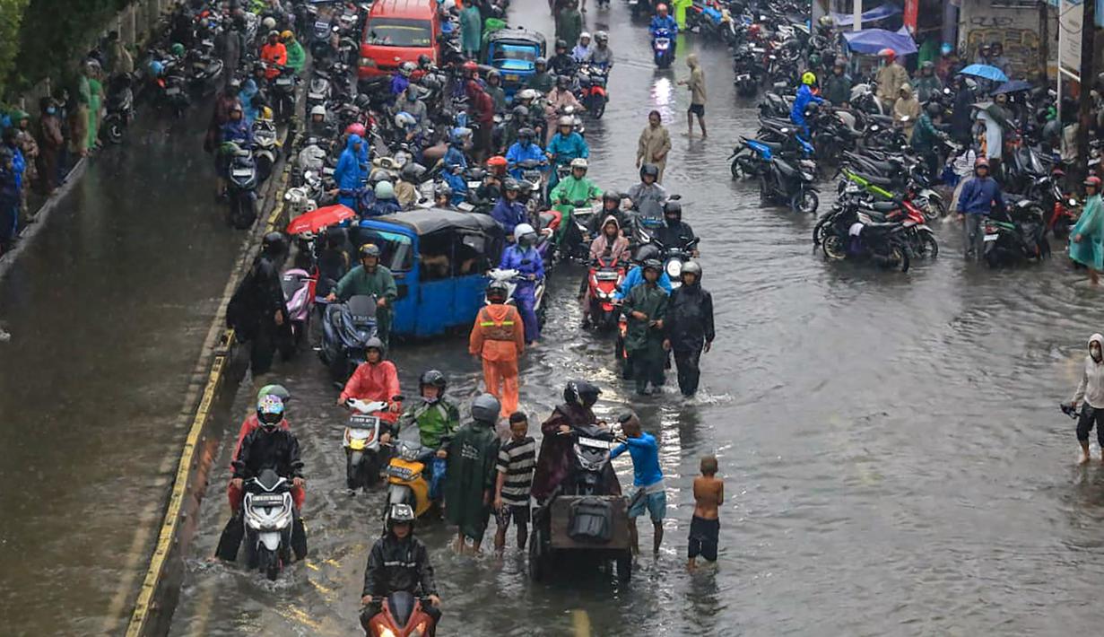 Meski kondisi jalan tergenang, sejumlah pengendara tetap melintas dengan berhati-hati untuk melanjutkan aktivitas. Tampak dalam foto, penumpukan pengendara terjebak banjir yang menggenangi Jalan Jembatan Tiga Raya, Jakarta Utara, Senin (12/1/2026). (merdeka.com/Arie Basuki)