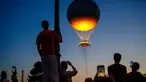 Orang-orang menyaksikan kaldron Olimpiade Paris 2024 saat matahari terbenam di Jardin des Tuileries di Paris pada 28 Juli 2024. (Dimitar DILKOFF/AFP)